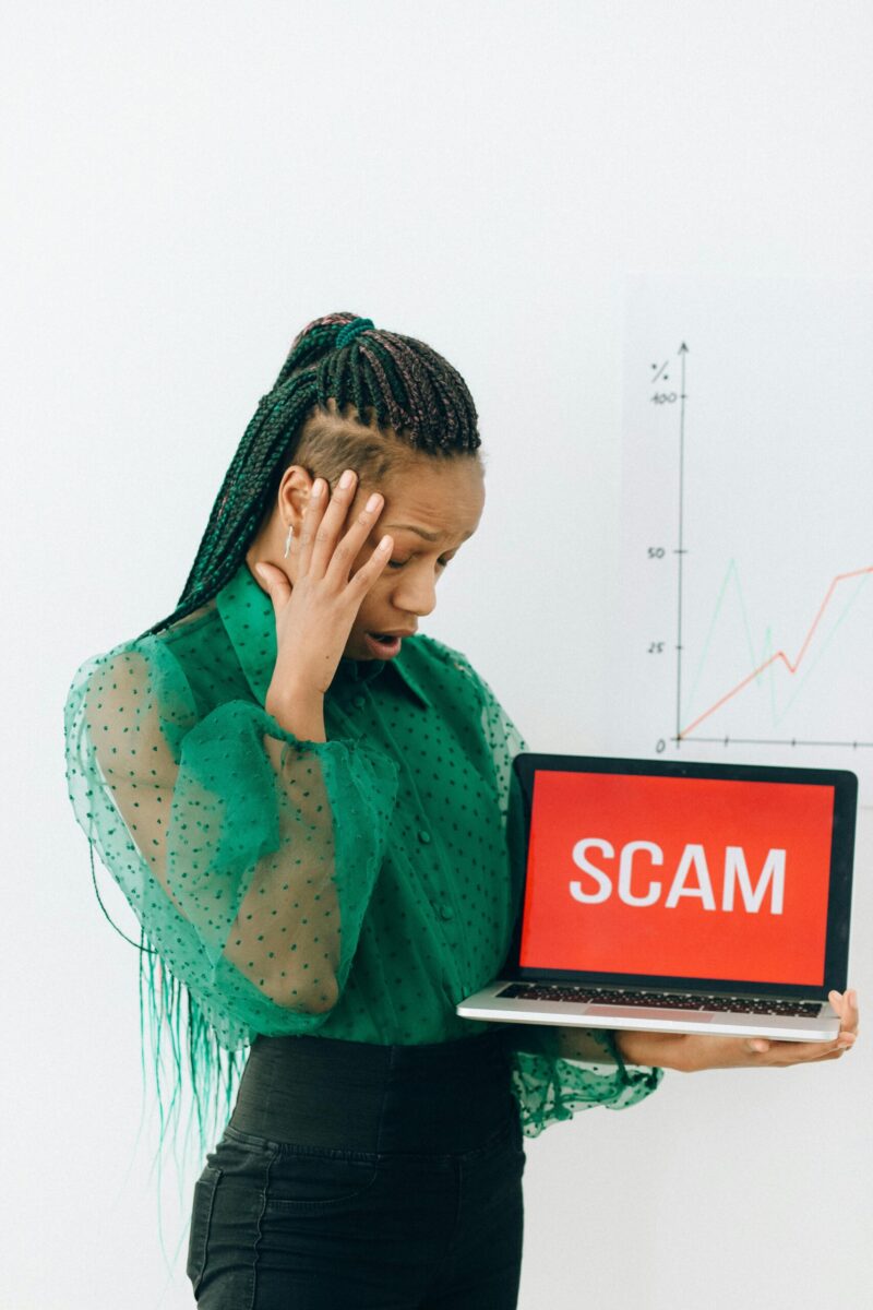 African American businesswoman shocked by scam alert on a laptop.